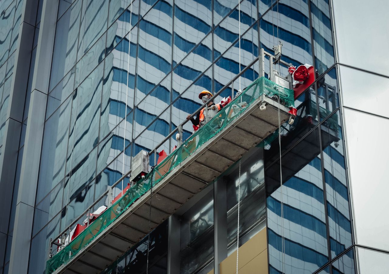 Urban worker washing windows on a tall building in Ho Chi Minh City, Vietnam.
